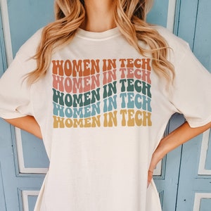 May include: A white t-shirt with the text "Women in Tech" repeated five times in a rainbow of colors, including pink, blue, green, and yellow.