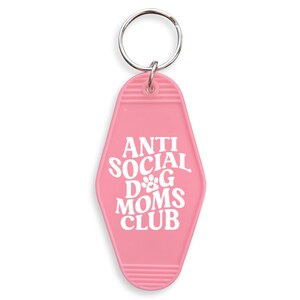May include: Pink motel key chain with the text "Anti Social Dog Moms Club" in white lettering.