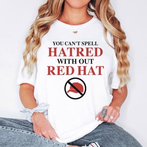 May include: White t-shirt with the text "You can't spell hatred without red hat" in red and a red baseball cap with a diagonal line through it.