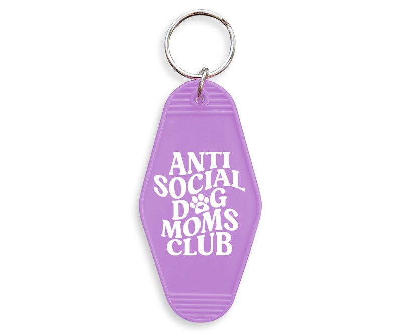 May include: Purple motel key chain with the text "Anti Social Dog Moms Club" in white lettering. The key chain has a paw print in the text.