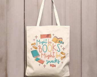 May include: A white canvas tote bag with a colorful design featuring the text "Might be BOOKS Might be snacks" and illustrations of books, snacks, and stars.