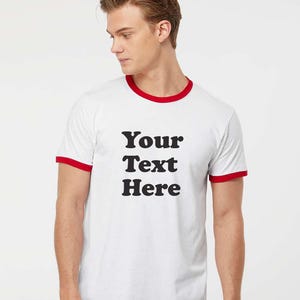 May include: White t-shirt with a red ringer and the text "Your Text Here" printed in black.