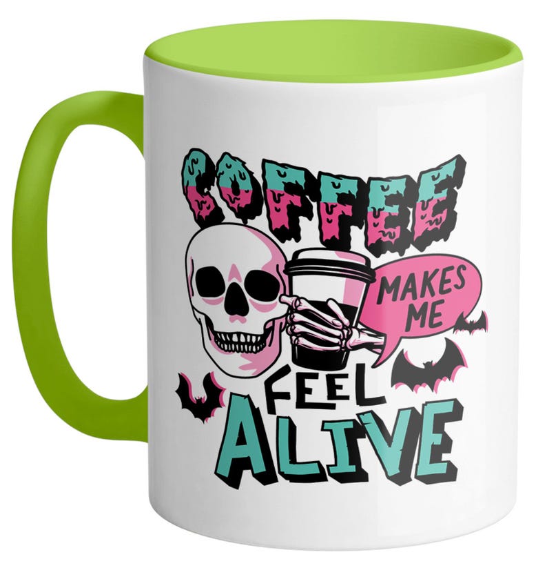 May include: White ceramic coffee mug with a green handle and interior. The mug features a skull graphic holding a coffee cup, with the text "COFFEE MAKES ME FEEL ALIVE" in a spooky font. Bats are also included in the design.