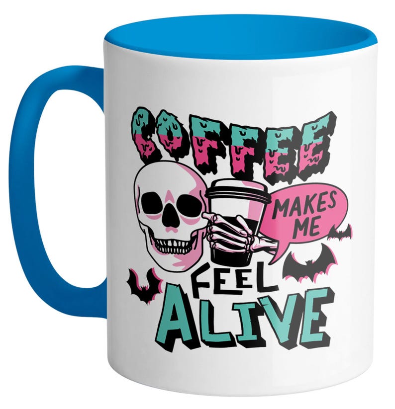 May include: White ceramic coffee mug with a blue handle and interior. The mug features a skull graphic holding a coffee cup, with the words "COFFEE MAKES ME FEEL ALIVE" in a spooky font, and bat illustrations.
