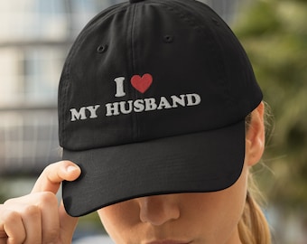 May include: Black baseball cap with white embroidery that reads "I love my husband" with a red heart.