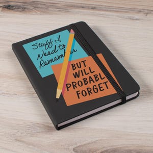 May include: Black notebook with the text "Stuff I Need to Remember" and "But Will Probabl Forget" on the cover. A yellow pencil graphic is also on the cover. The notebook has an elastic band closure.