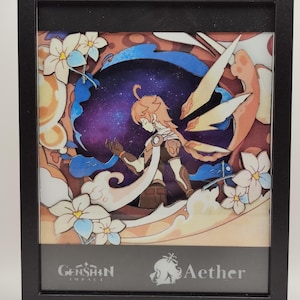 Peut inclure: Une œuvre d'art en papier découpé encadrée représentant un personnage du jeu vidéo Genshin Impact. Le personnage est Aether, un jeune homme aux cheveux orange, debout dans un ciel étoilé avec un fond bleu et blanc. L'œuvre d'art est encadrée en noir et porte le logo Genshin Impact et le mot "Aether" en bas.