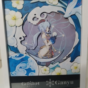 Puede incluir: Una pieza de arte de papel con Ganyu del videojuego Genshin Impact. La imagen muestra a Ganyu de pie en un paisaje azul y blanco con un copo de nieve y el texto "Ganyu" en la parte inferior.