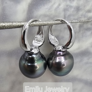May include: A pair of silver hoop earrings with black pearl drops. The pearls have a slight iridescent sheen.