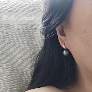 May include: A pair of silver hoop earrings with a single black pearl dangling from each hoop.