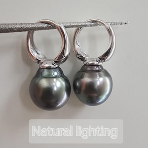 May include: A pair of silver hoop earrings with black pearl drops. The earrings are photographed on a white surface with natural lighting.