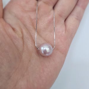 May include: A delicate silver chain necklace with a single, large, pale pink pearl pendant.
