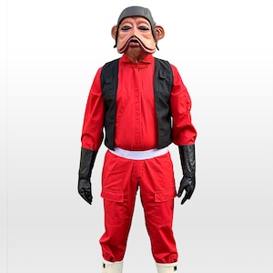 Könnte beinhalten: Ein roter Overall mit einer schwarzen Weste und einem weißen Gürtel. Die Person, die den Overall trägt, hat eine braune und schwarze Maske mit großen Augen.