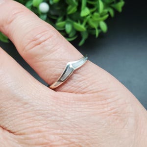 May include: A silver ring with a white mother of pearl inlay in the shape of a chevron.