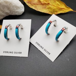 Puede incluir: Un par de pendientes de aro de plata de ley con incrustaciones de turquesa, rojo y blanco. Los pendientes se muestran en una tarjeta blanca con el texto "Sterling Silver".