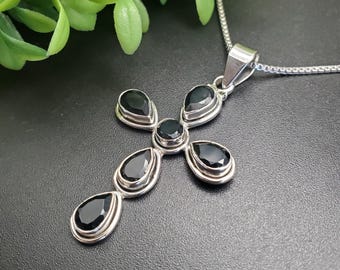 Op de afbeelding: Een zilveren kruis ketting met zwarte edelstenen. Het kruis is gemaakt van vijf druppelvormige stenen.