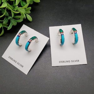 Puede incluir: Un par de pendientes de aro de plata de ley con incrustaciones de turquesa, malaquita y coral rojo. Los pendientes se muestran en tarjetas blancas con el texto "Sterling Silver".
