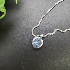 May include: A silver heart-shaped pendant necklace with a silver chain. The back of the pendant has the inscription "925 Italy" on it.
