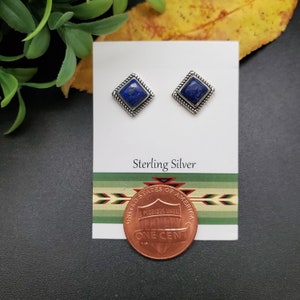 May include: A pair of sterling silver earrings with square blue lapis lazuli stones. The earrings are shown next to a US penny for size comparison.