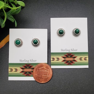 May include: A pair of sterling silver earrings with green malachite stones. The earrings are displayed on a white card with the words "Sterling Silver" printed on it. A penny is included for size reference.