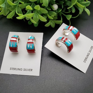 May include: A pair of sterling silver hoop earrings with turquoise, red, and white inlay. The earrings are displayed on a white card with the text "STERLING SILVER".