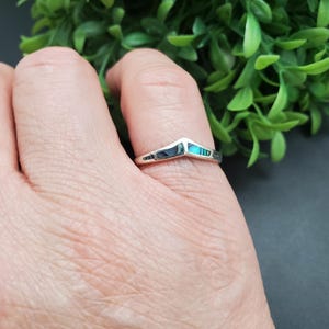 May include: A silver ring with a chevron shaped inlay of iridescent abalone shell.