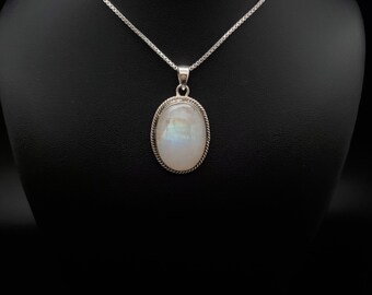 May include: A silver necklace with an oval, iridescent moonstone pendant. The pendant is framed with a twisted rope design. The necklace is displayed against a black background.