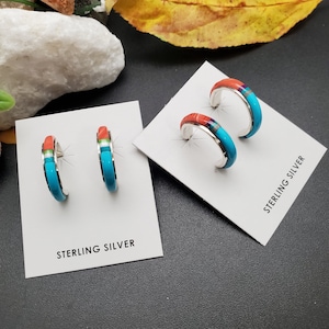 May include: A pair of sterling silver hoop earrings with turquoise and coral inlay. The earrings are displayed on a white card with the text "Sterling Silver".