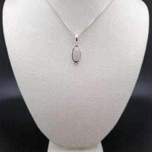 May include: A silver chain necklace with a white oval moonstone pendant.