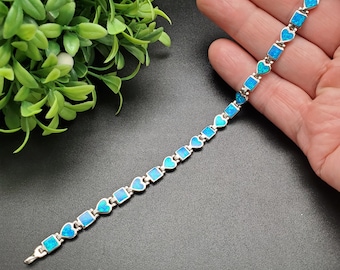 May include: A silver bracelet with blue opal heart and square shaped charms.