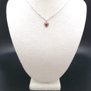 May include: A silver necklace with a small red heart pendant.
