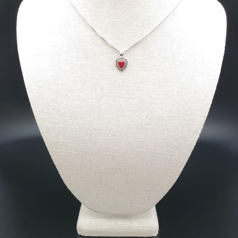 May include: A silver necklace with a small red heart pendant.