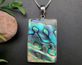 May include: A silver chain necklace with a rectangular abalone shell pendant. The shell has iridescent blue, green, and purple colors.
