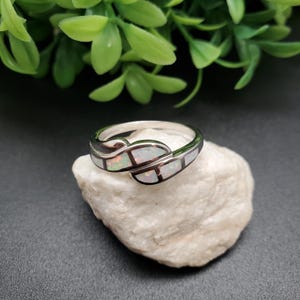 May include: A silver ring with white opal stones set in a leaf design.