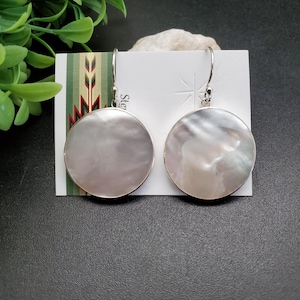 May include: A pair of silver dangle earrings with round white mother of pearl stones.