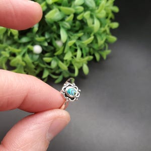 May include: A silver ring featuring a blue and green abalone shell inlay set within a floral design.