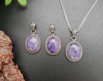 Peut inclure: Trois pendentifs en argent avec des pierres marbrées violettes et blanches. Les pendentifs sont de forme ovale et ont une bordure argentée décorative. Les pierres sont serties dans une bélière en argent.