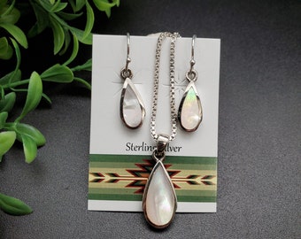 May include: A set of sterling silver jewelry featuring a teardrop-shaped pendant and matching earrings. The pendant and earrings are made of white mother-of-pearl with a pearlescent sheen. The jewelry is displayed on a white card with the text "Sterling Silver".