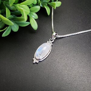 May include: A silver chain necklace with a silver oval pendant featuring a white moonstone.