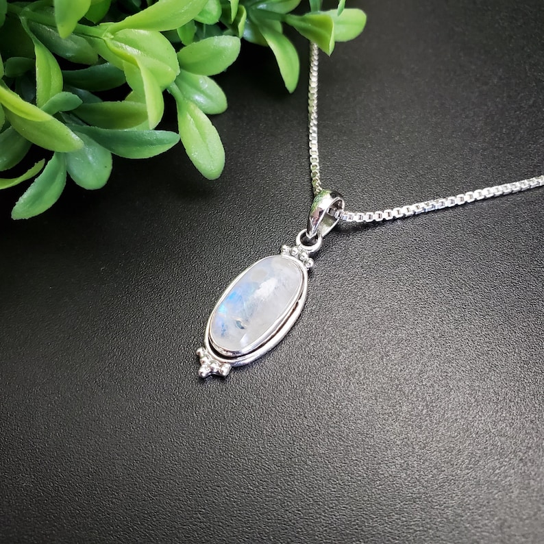 May include: A silver chain necklace with a silver oval pendant featuring a white moonstone.
