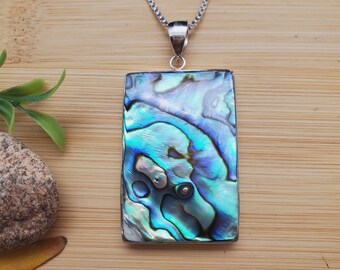 May include: A silver chain necklace with a rectangular abalone shell pendant. The shell has iridescent blue, green, and purple colors.