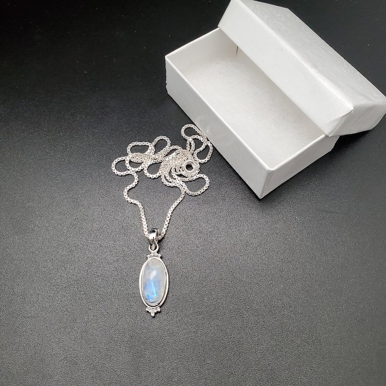 May include: A silver chain necklace with a silver oval pendant featuring a blue moonstone.