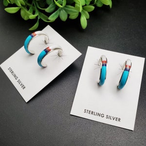 Puede incluir: Dos pares de pendientes de aro de plata de ley con incrustaciones de turquesa, rojo y azul. Los pendientes se muestran en tarjetas blancas con el texto "Sterling Silver".