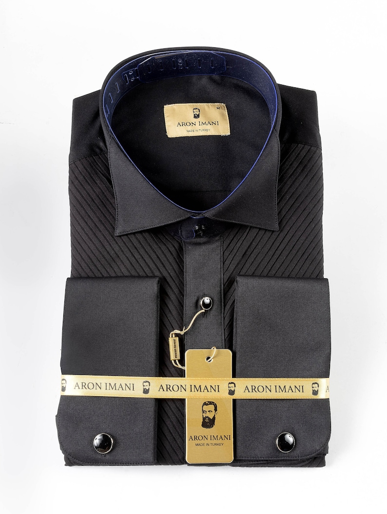 May include: A black dress shirt with a pleated front and French cuffs. The shirt has a gold label with the text "ARON IMANI" and a small beard icon. The shirt is made in Turkey.