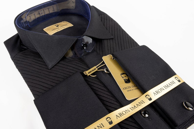 May include: Black dress shirt with a pleated front and French cuffs. The shirt has a gold label with the text "ARON IMANI" and a small image of a man with a beard. The shirt is also adorned with a gold ribbon with the text "ARON IMANI" and a small image of a man with a beard.