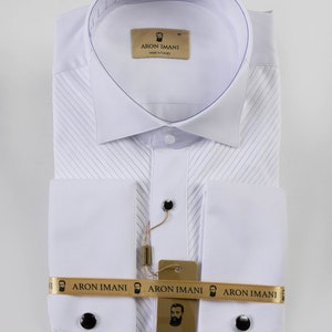 May include: White dress shirt with a pleated front and French cuffs. The shirt has a gold label with the text "ARON IMANI" and a small image of a man with a beard. The shirt is made in Turkey.