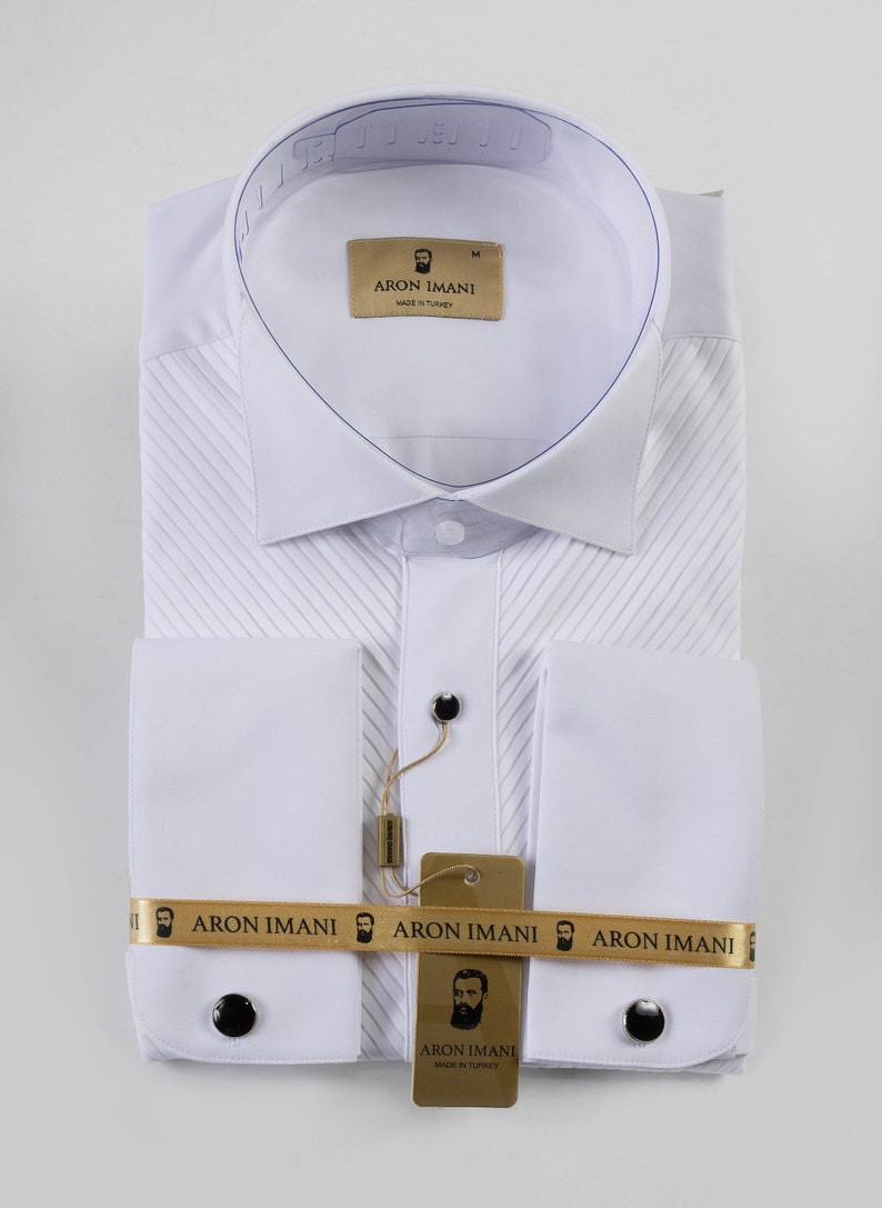 May include: White dress shirt with a pleated front and French cuffs. The shirt has a gold label with the text "ARON IMANI" and a small image of a man with a beard. The shirt is made in Turkey.