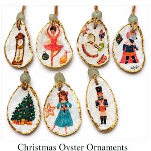 May include: Seven oyster shell ornaments with gold-painted edges, each featuring a unique Christmas-themed illustration including a grandfather clock, ballerina, rocking horse, mouse, tree, girl, and nutcracker, suspended by twine with a bead.