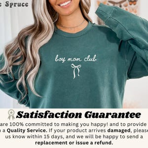 K&ouml;nnte beinhalten: Ein teal-farbenes Sweatshirt mit dem Text "boy mom club" in wei&szlig;er Schrift und einer Schleifen-Grafik. Das Sweatshirt ist aus weichem Material und hat lange &Auml;rmel. Die Worte "Blue Spruce" stehen oben links.