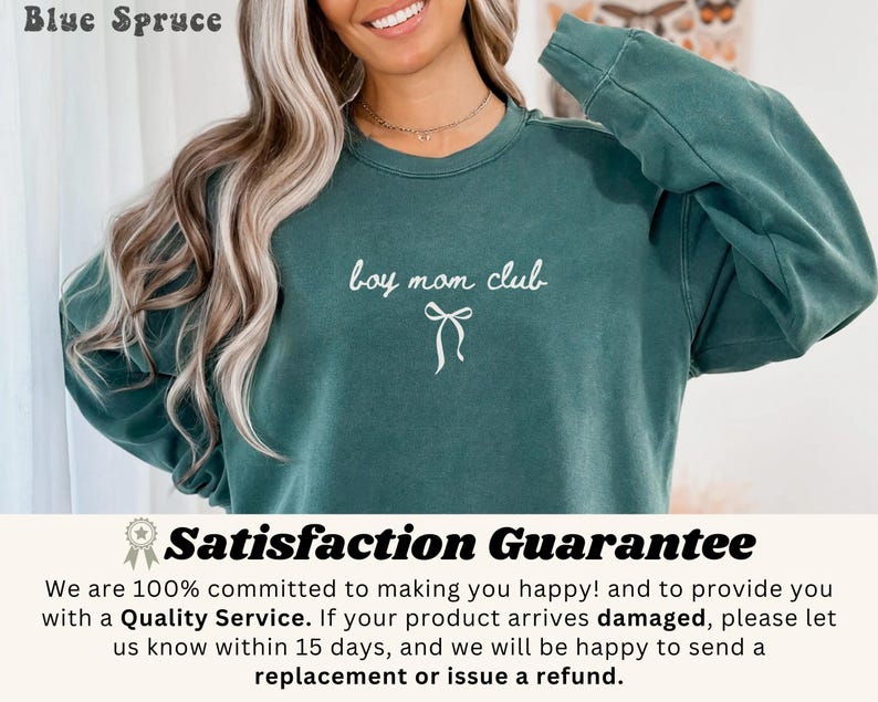 K&ouml;nnte beinhalten: Ein teal-farbenes Sweatshirt mit dem Text "boy mom club" in wei&szlig;er Schrift und einer Schleifen-Grafik. Das Sweatshirt ist aus weichem Material und hat lange &Auml;rmel. Die Worte "Blue Spruce" stehen oben links.